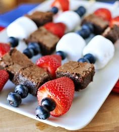 a white plate topped with brownies covered in marshmallows and strawberries