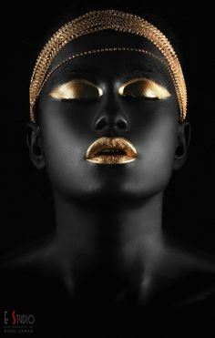 a woman's face is covered in gold and black makeup, with her eyes closed