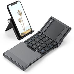 an open laptop computer sitting on top of a table next to a cell phone holder