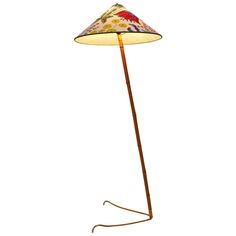 a floor lamp with a flowered shade on the base and a long wooden pole