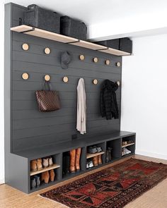 a coat rack with shoes and purses hanging on the wall next to a rug