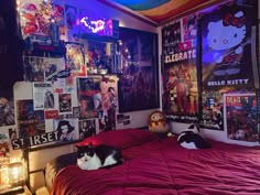 two black and white cats laying on a bed in a room with posters all over the wall