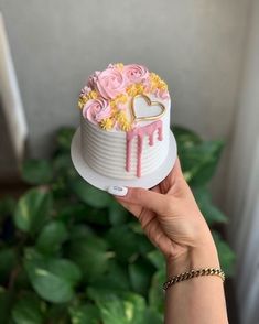 a person holding a cake with flowers on it