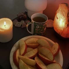 an apple cut in half on a plate next to a lit candle and some rocks