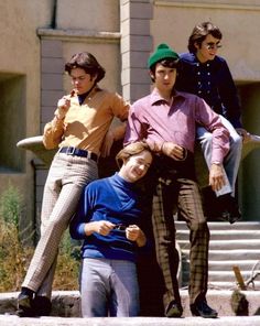 four young men posing for a photo in front of a building with stairs and steps