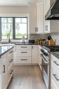 a kitchen with white cabinets and stainless steel appliances, along with wood flooring in the middle