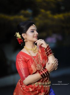 a woman in red and blue sari with gold jewelry on her neck, posing for the camera