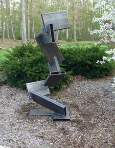 a metal sculpture sitting in the middle of a forest