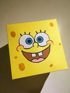 a hand holding up a yellow card with an image of spongebob on it