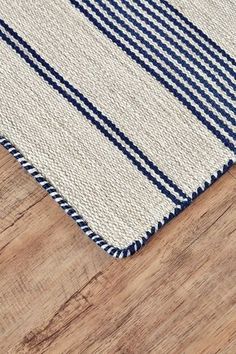 a close up of a rug on a wooden floor with a blue and white stripe pattern