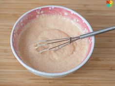 a bowl filled with batter and whisk on top of a wooden table