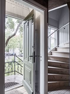 an open door leading to a porch with stairs and trees in the backgroud