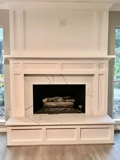 an empty living room with a fireplace and large windows