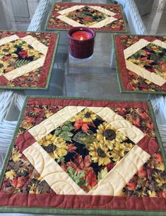 three quilted placemats sitting on top of a table next to a candle