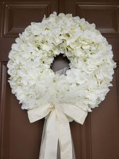 a wreath with white flowers is hanging on the front door