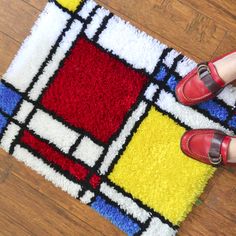 a pair of red shoes standing on top of a colorful area rug next to a woman's legs