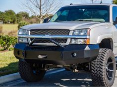 a silver truck is parked on the side of the road in front of some bushes