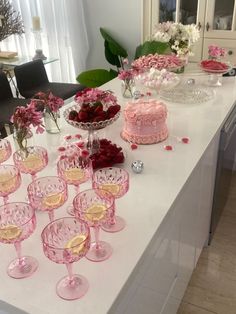 a table topped with lots of pink and white cake next to glasses filled with flowers