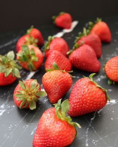 a bunch of strawberries sitting on top of a black counter next to each other