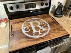 a wooden cutting board sitting on top of an oven with a monogrammed design