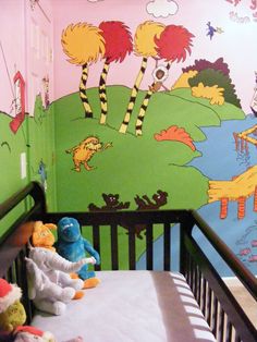 there is a crib with stuffed animals on it in front of a wall mural