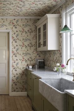 a kitchen with floral wallpaper and marble counter tops