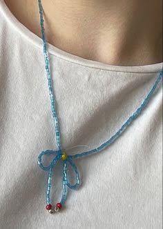 a woman wearing a white shirt and blue beaded necklace with a bow on it