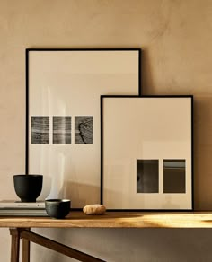 three framed photographs sit on a wooden table