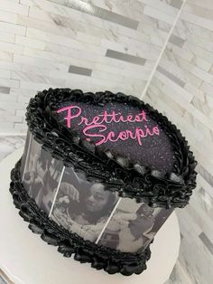 a black and white cake with pink writing on it