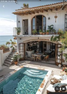 an outdoor swimming pool in front of a house next to the ocean with patio furniture and potted plants