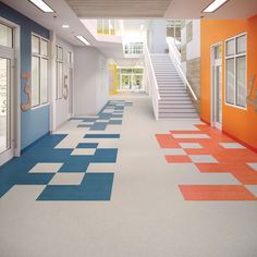 an empty hallway with blue, orange and white floor tiles on the ground next to stairs