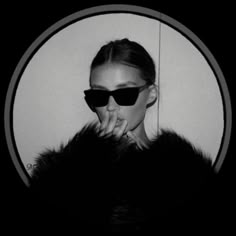 a woman wearing sunglasses and a fur coat is posing for the camera with her hand on her face