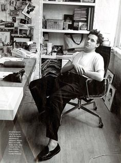 a black and white photo of a man sitting in a chair with his feet up