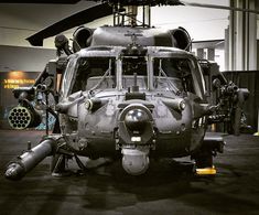 an army helicopter sits on display in a building with people standing around it and looking at the camera