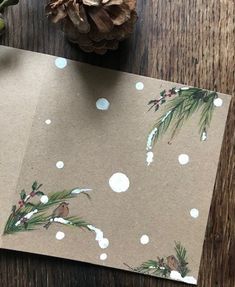 a piece of brown paper with white polka dots and pine cones on it next to a pine cone