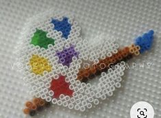 a close up of a cross stitch beaded object on a white surface with the word love written across it