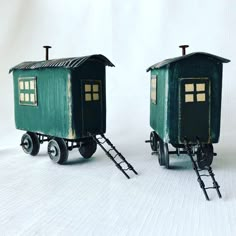 two small green train cars sitting next to each other on top of a white surface