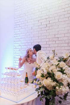 a bride and groom are kissing in front of a table with champagne glasses on it