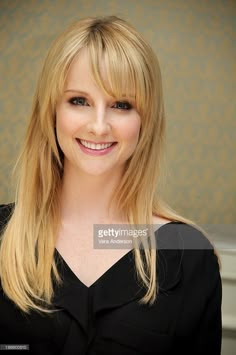 a woman with long blonde hair smiling at the camera