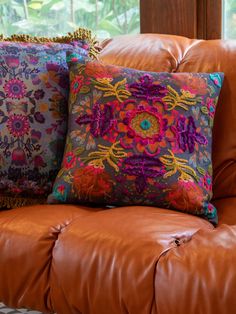 three decorative pillows on a brown leather couch