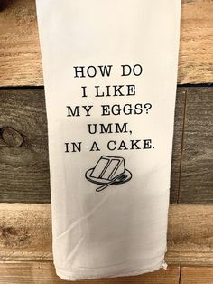 a tea towel hanging on the side of a wooden door that says, how do i like my eggs? umm in a cake