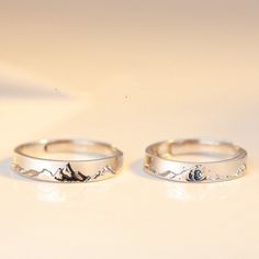 two silver rings sitting next to each other on a white surface with an eye in the middle