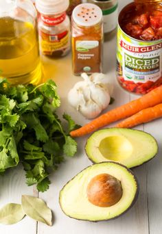 an avocado, carrots, cilantro, and other ingredients on a table