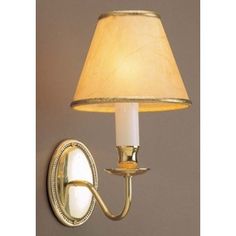 a wall light with a white shade on it and a mirror behind the light fixture