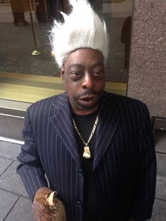 a man in a suit with white hair holding a banana and looking at the camera