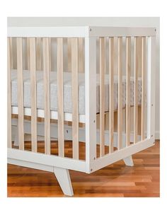 a white crib with wooden slats on the floor