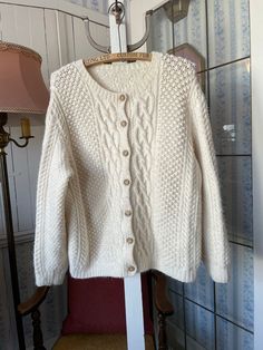 "This gorgeous \"fisherman\" sweater was knit by hand from a wool blend in traditional creamy ivory/off white, using a variety of fancy knitting stitches. The sweater fastens in the front with the original wood buttons; please note that one has been chipped. The measurements, taken with the sweater lying flat, are: shoulder to shoulder, 17 inches; armpit to armpit, 21 1/2 inches; sleeves, 23 inches; length, 23 inches; bottom edge, 19 inches (with stretchy ribbing). The sweater overall has quite a bit of stretch. In very good condition." Cream Wool Hand-knitted Sweater, Hand-knitted Cream Wool Sweater, Hand Knitted Wool Cream Sweater, Cream Hand Knitted Wool Sweater, Cream Wool Knitted Sweater Coat, Cream Knitted Wool Sweater Coat, Classic Chunky Knit Cream Sweater, Cream Chunky Knit Classic Sweater, Classic Cream Chunky Knit Sweater