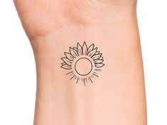 a small sunflower tattoo on the left side of the wrist is shown in black ink