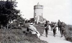 a group of people walking down a path next to a tall tower