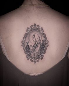 the back of a woman's shoulder with a portrait of a woman in a frame